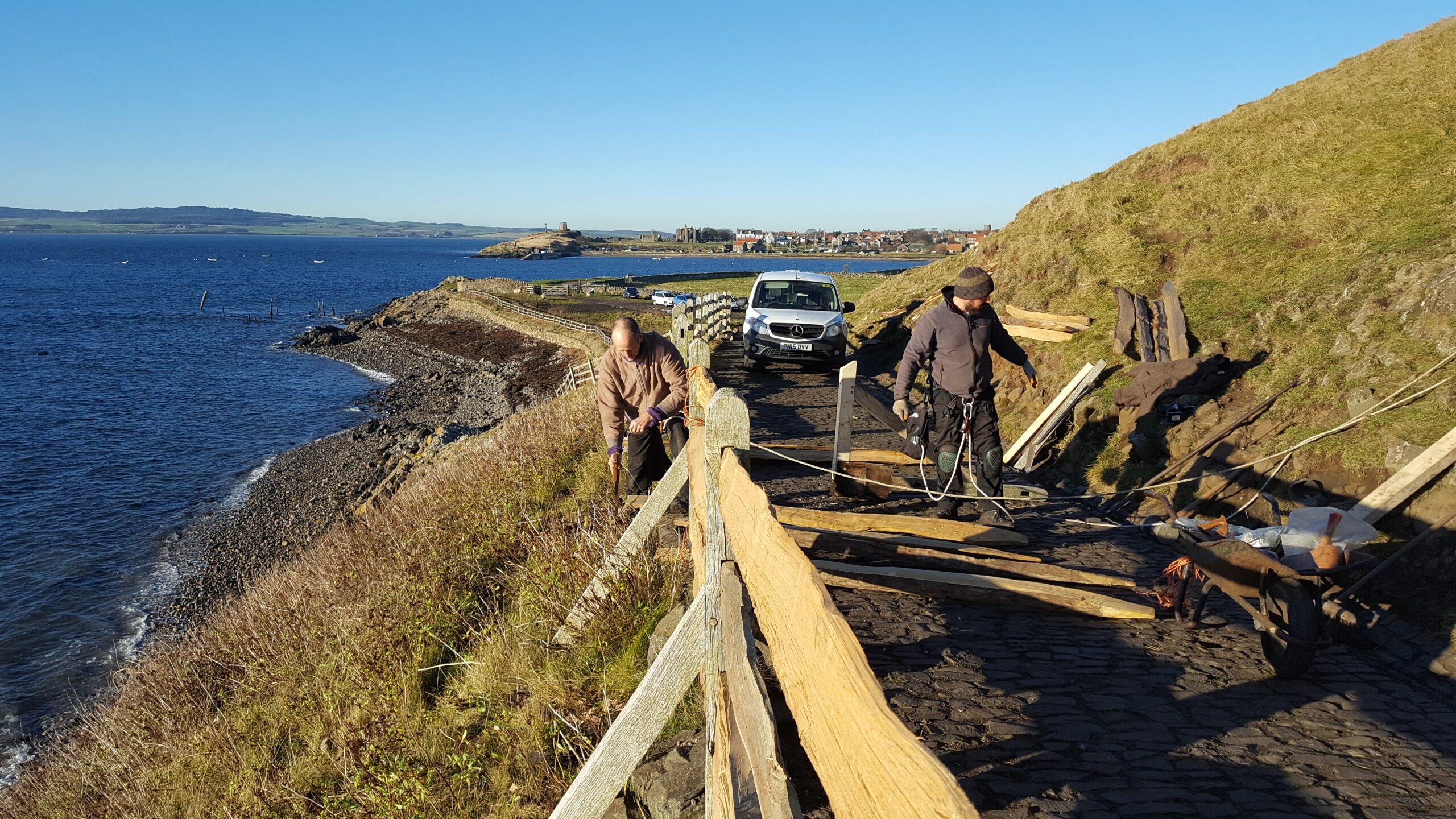 Replacing the old cleft oak rails and some of the sawn posts with new cleft chestnut, here on the access ramp up to Lindisfarne Castle.